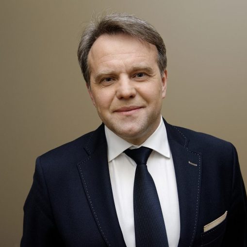 Vyras su kostiumu ir tamsiai mėlynais kaklaraiščiu.