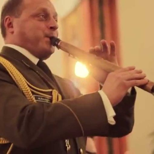 Vyras karininko uniforma groja mediniu pučiamuoju instrumentu.