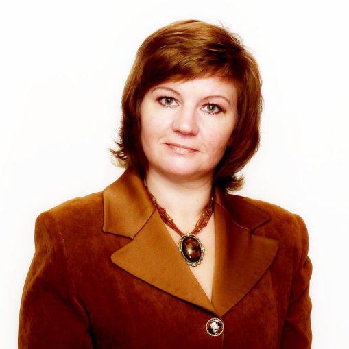 Portretas: moteris rudu švarkeliu ir karoliais su dideliu akmeniu.