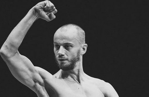 Juodai baltas portretas vyro, demonstruojančio savo bicepsą.