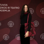 Moteris su rankine ir užrašu "Lietuvos muzikos ir teatro akademija" fone.